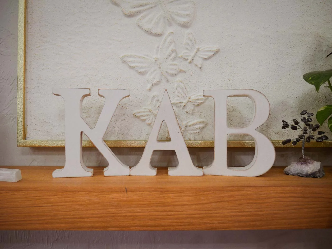 White KAB letters on a wooden shelf in the salon